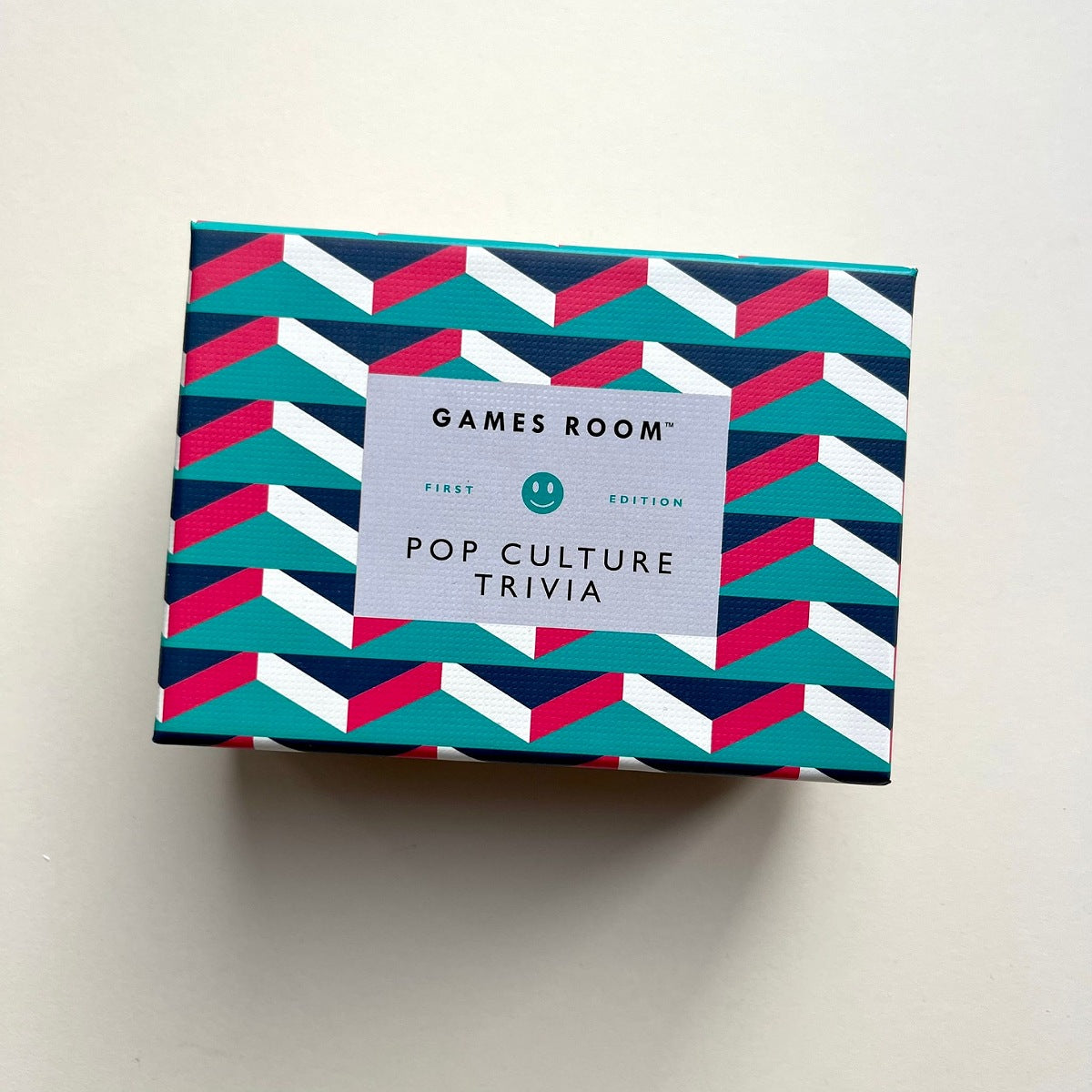 Games Room 'Pop Culture Trivia' game box featuring a colorful geometric pattern of teal, navy, pink, and white stripes with a light grey label in the center.