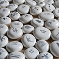 White stones with black motivational inscriptions and designs arranged on a wooden surface