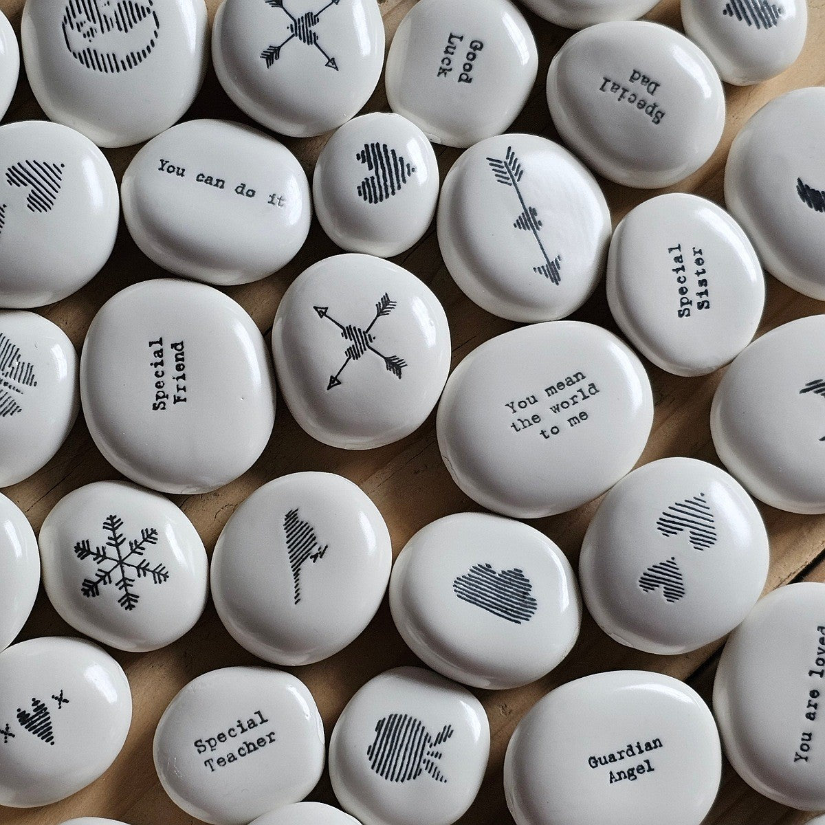 White stones with black inscriptions and symbols on a wooden surface