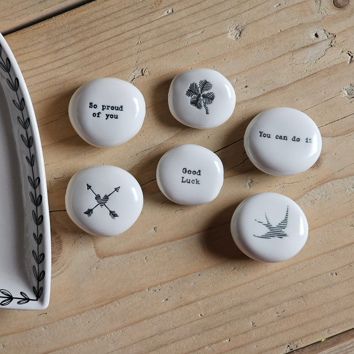 Set of white ceramic stones with motivational phrases on a wooden surface