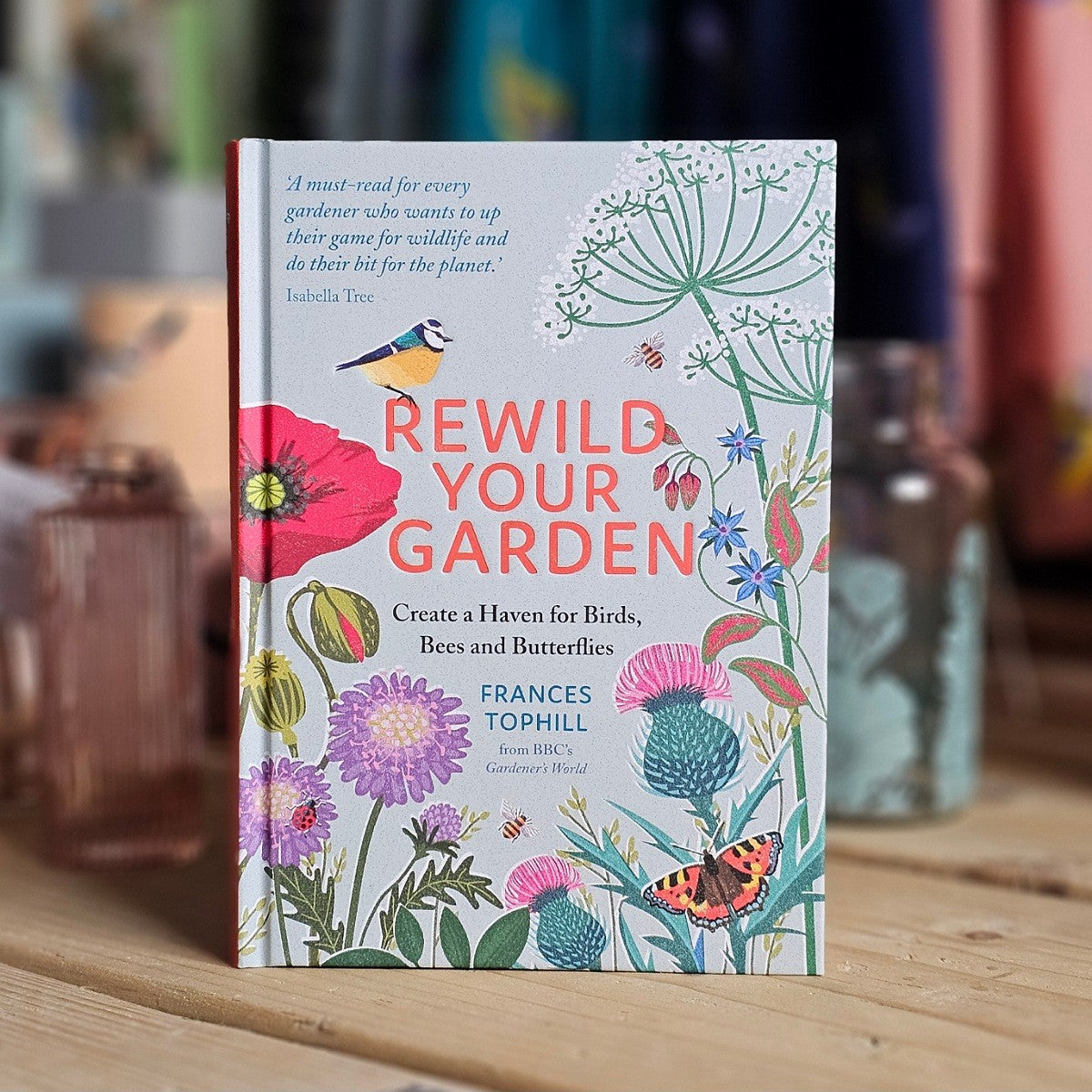 Book titled 'Rewild Your Garden' with floral and nature-themed cover on a wooden surface.