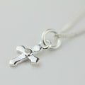 Silver cross pendant necklace on a light gray background
