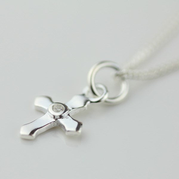 Silver cross pendant necklace on a light gray background