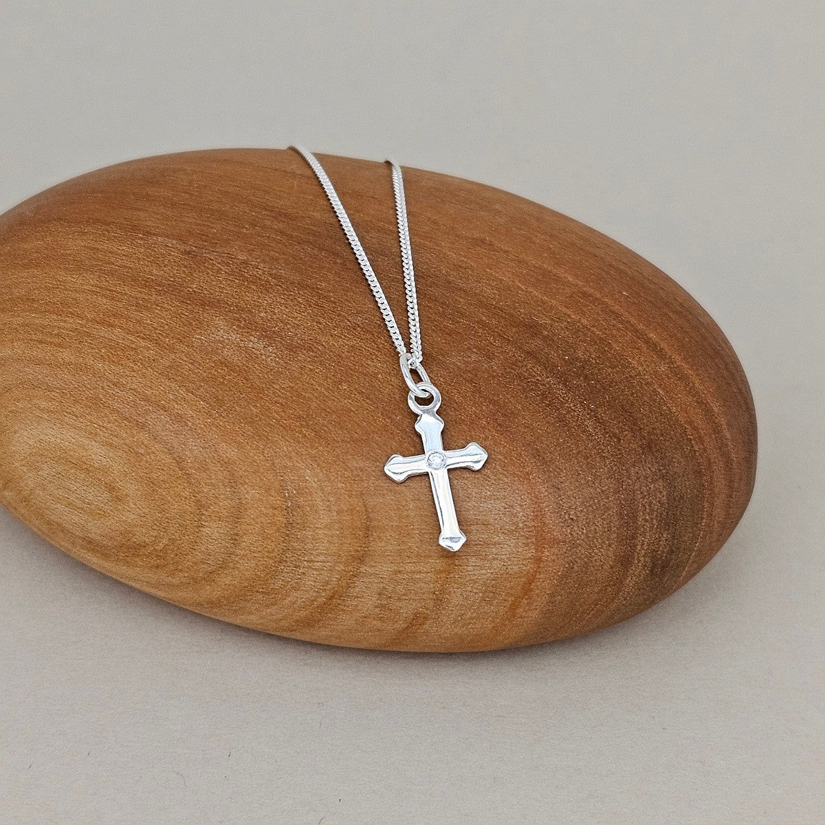 Silver cross necklace on a wooden rock