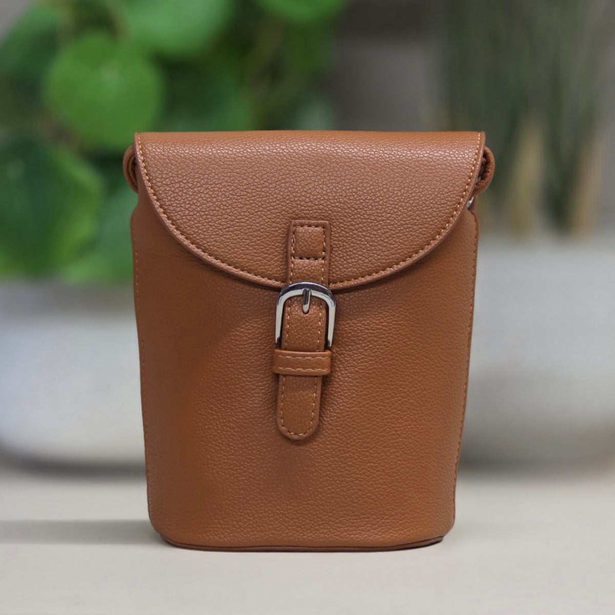 Brown leather pouch with a buckle on a blurred background
