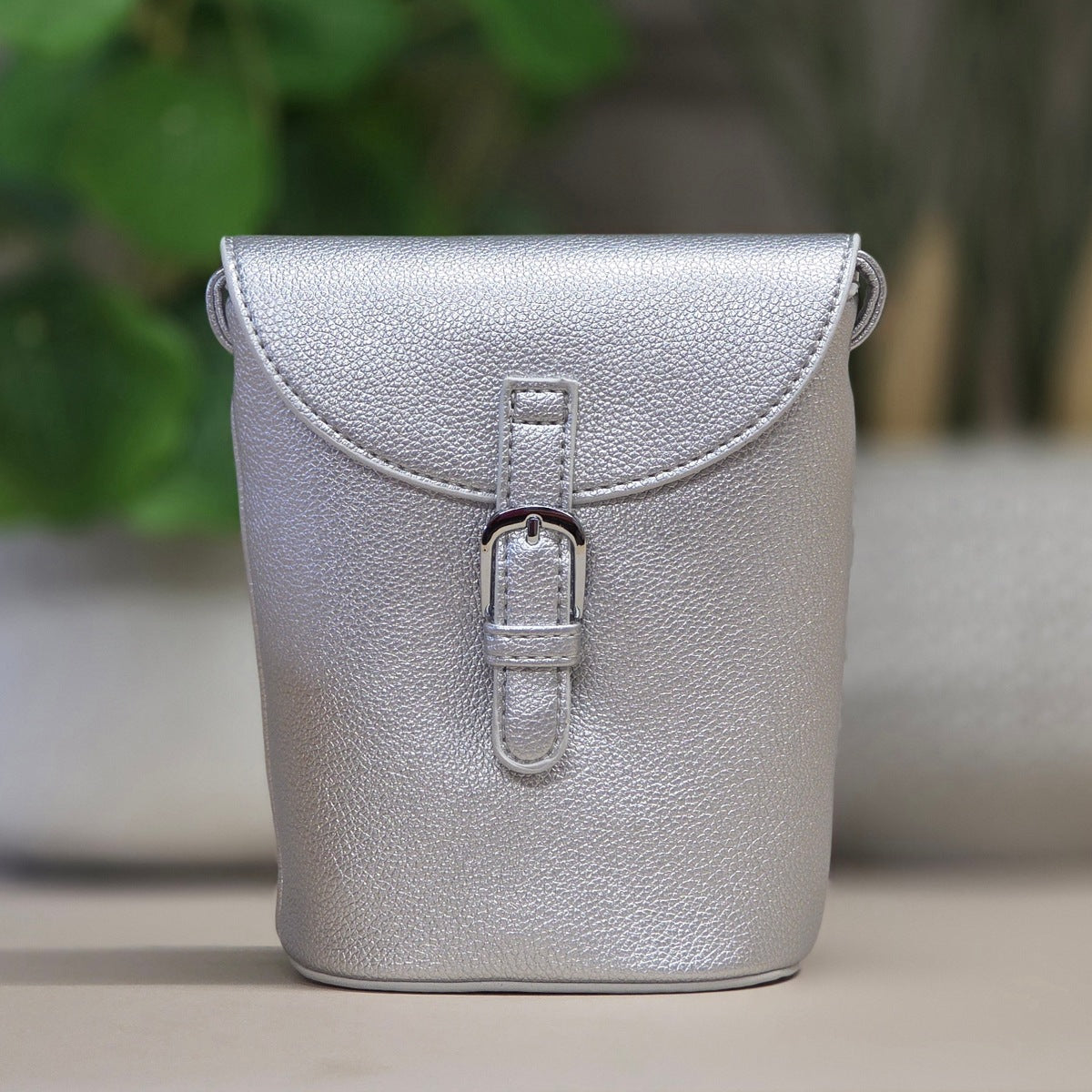 Silver leather bag with a buckle on a blurred background