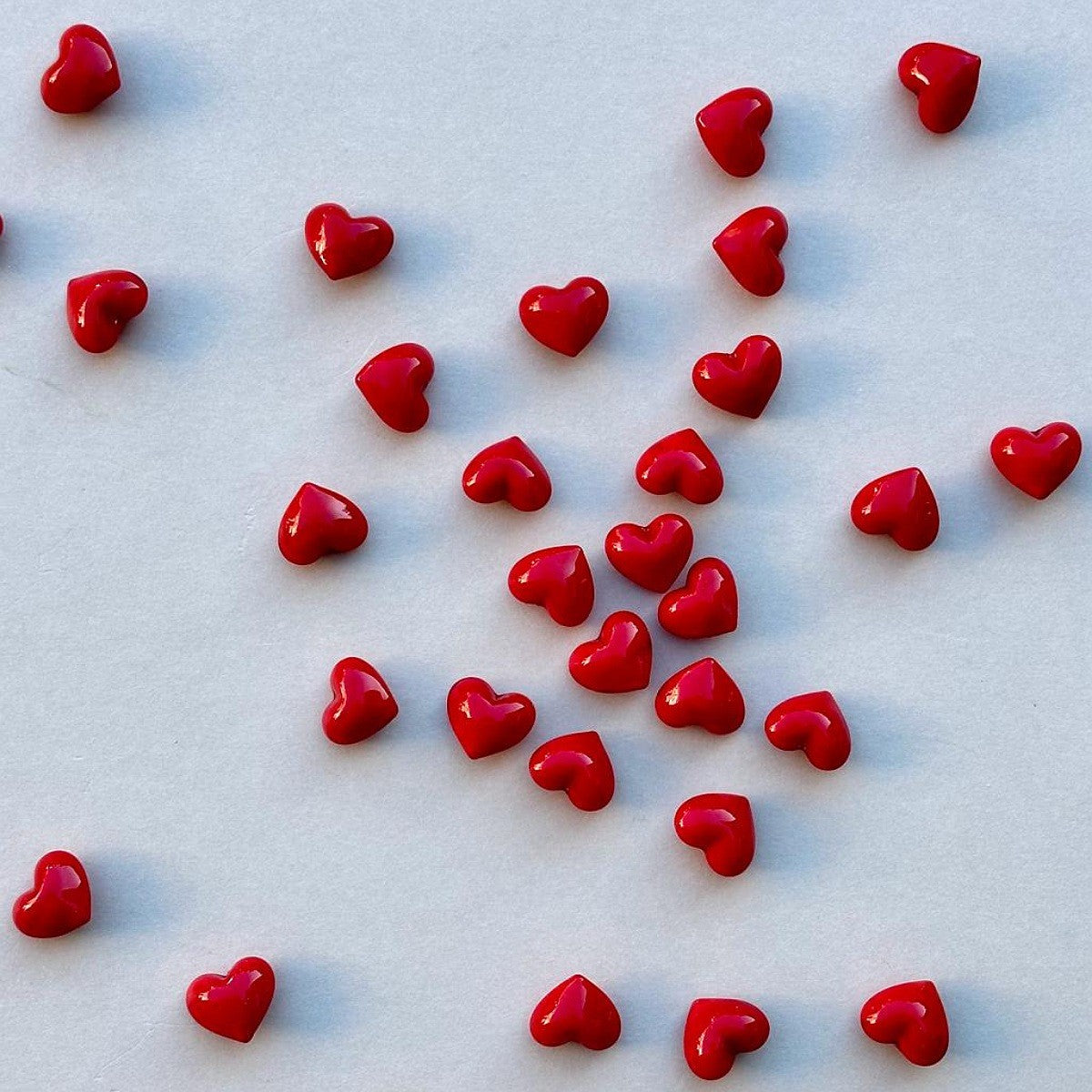 Small red heart-shaped glass scattered on a light-coloured surface