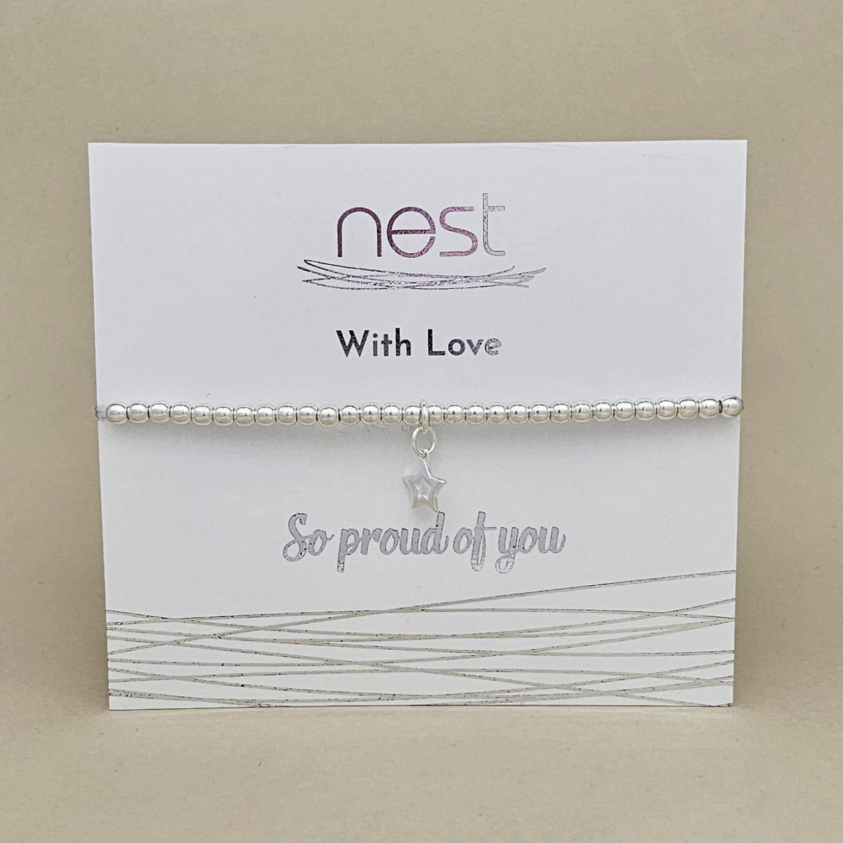 A silver beaded bracelet with a dangling star charm, presented on a white card from the brand 'nest' that reads 'With Love' and 'So proud of you'.