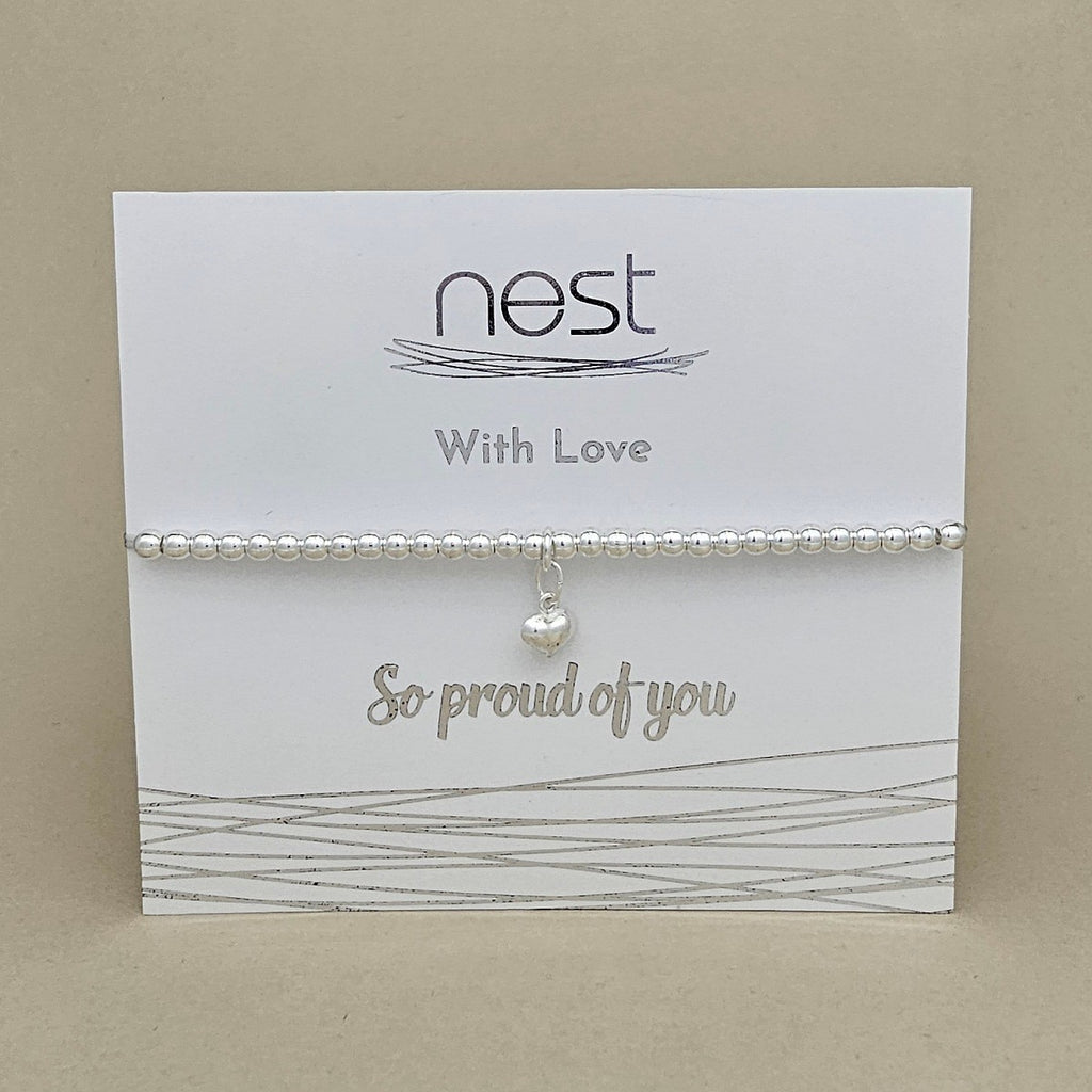 A silver beaded bracelet with a small pearl charm, displayed on a white card from the brand 'nest' that reads 'With Love' and 'So proud of you'.