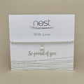 A silver beaded bracelet with a small pearl charm, displayed on a white card from the brand 'nest' that reads 'With Love' and 'So proud of you'.