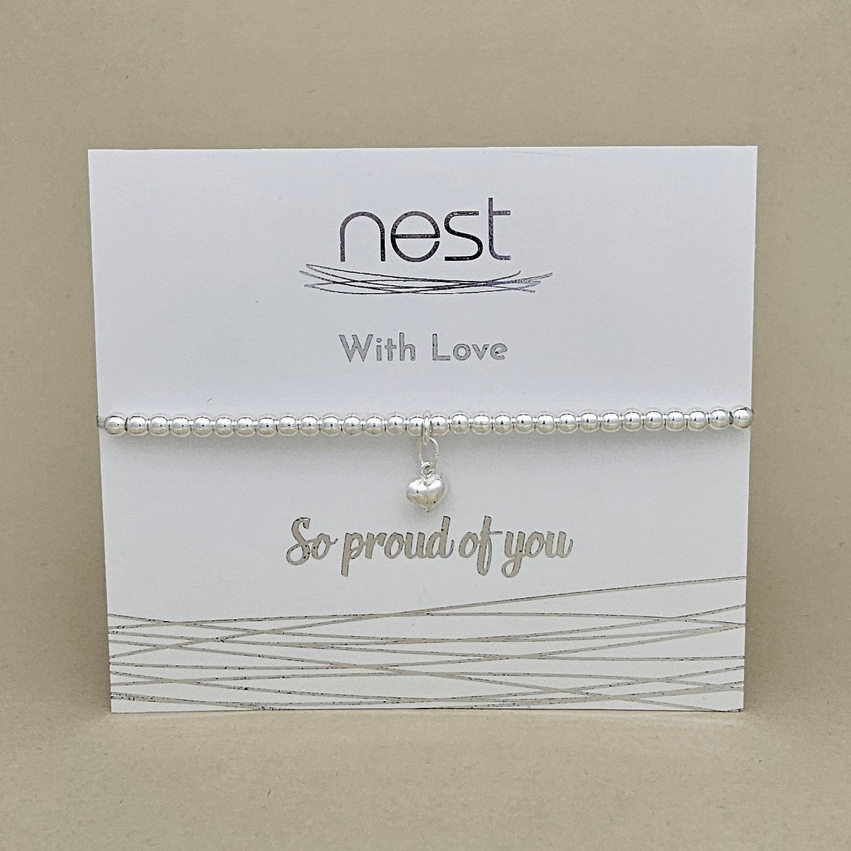 A silver beaded bracelet with a small pearl charm, displayed on a white card from the brand 'nest' that reads 'With Love' and 'So proud of you'.