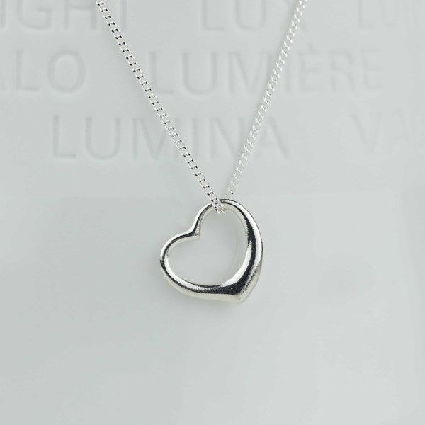 A silver open heart pendant necklace on a delicate silver chain, displayed against a light gray background with faint embossed text.