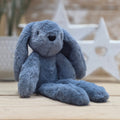 A blue soft fuzzy plush bunny toy, with black eyes and nose, on a wooden surface with a blurred star-shaped object in the background
