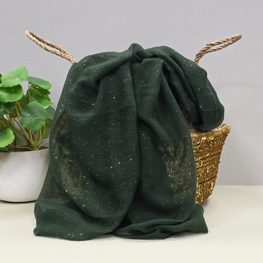 Green sheer fabric with a gentle sparkle. A plant and basket in the background
