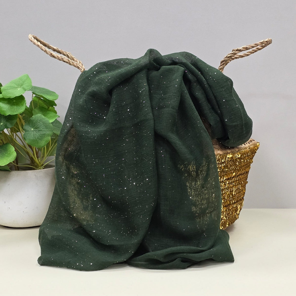 Green sheer fabric with a gentle sparkle. A plant and basket in the background