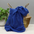 Blue sheer fabric with glittery texture in a woven basket against a grey background
