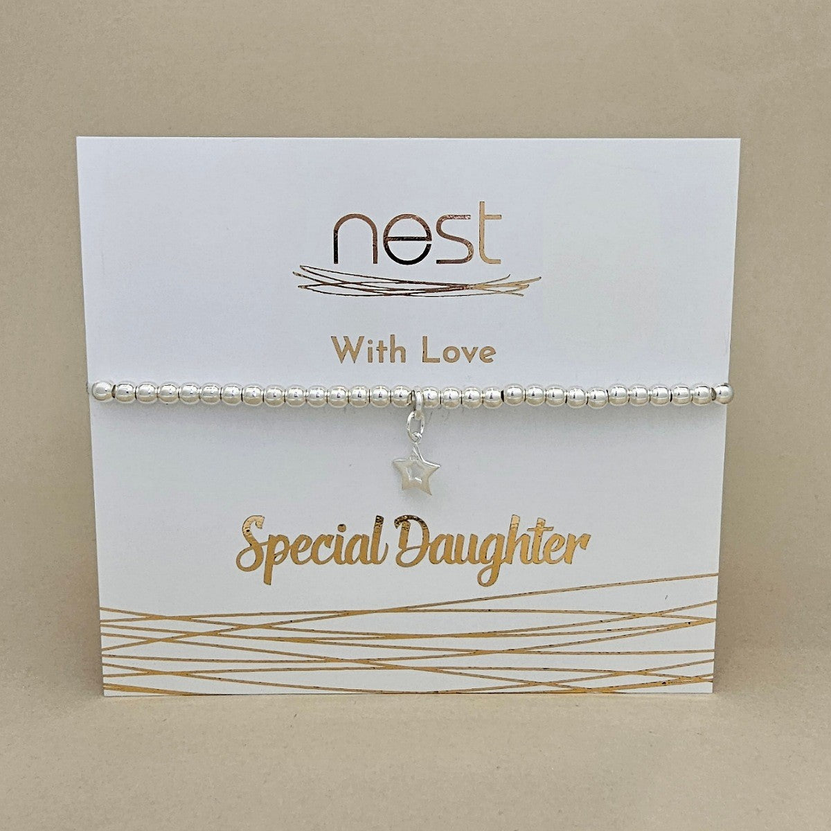 A silver beaded bracelet with a dangling star charm, presented on a white display card with gold foil text reading 'nest With Love Special Daughter' against a beige background.