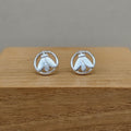 Pair of silver moth earrings on a wooden surface with a gray background