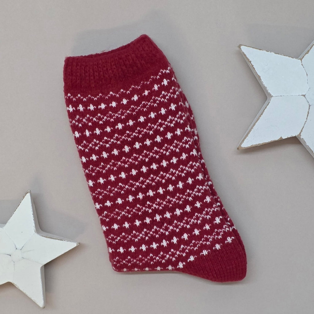 Red knitted sock with white pattern on a light grey background