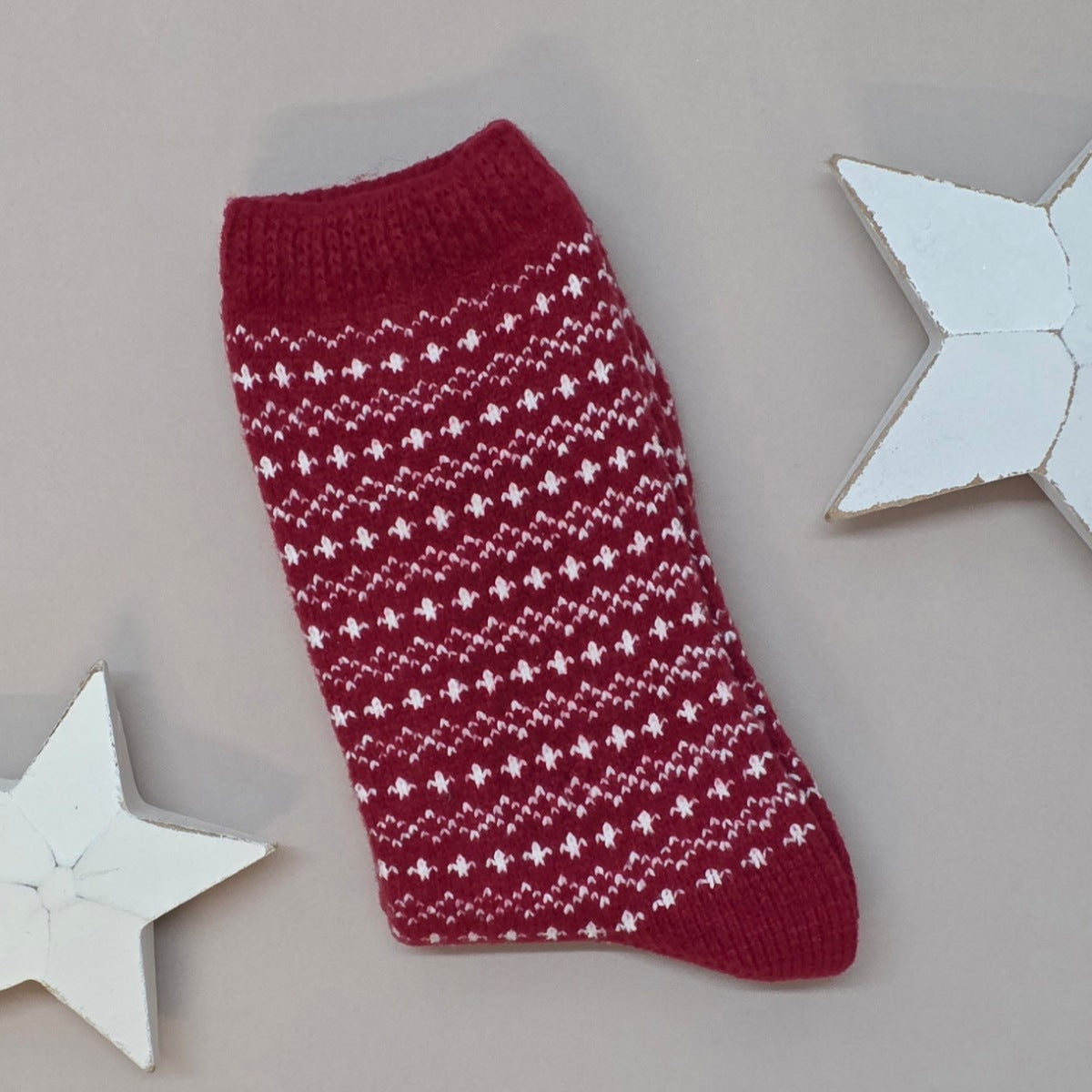 Red knitted sock with white pattern on a light grey background