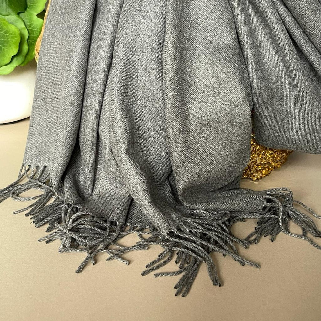 Gray scarf with fringes draped over a surface