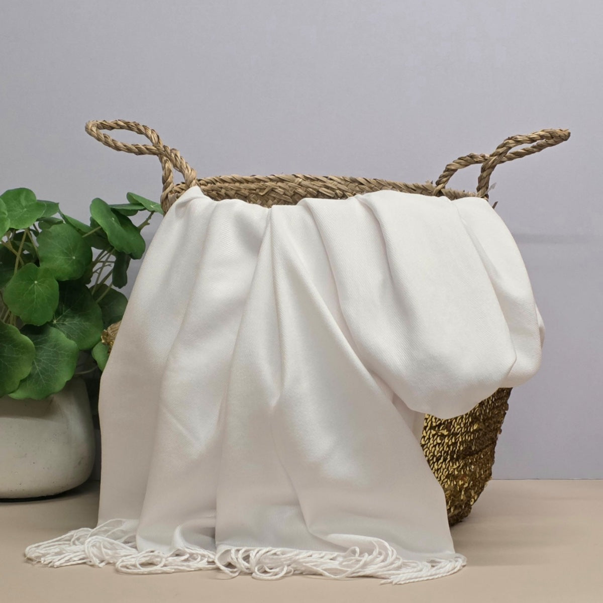 White fabric draped over a woven basket with a plant in the background