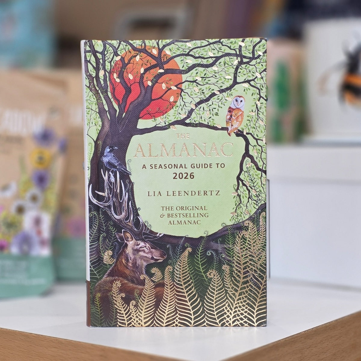 A book entitled 'The Almanac' a seasonal guide to 2026 by Lia Leendertz with nature-themed design featuring animals and trees on a blurred background