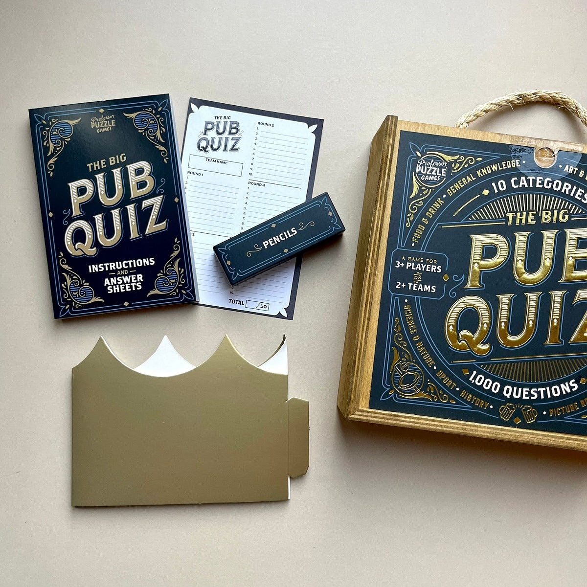 Wooden box with words 'The Big Pub Quiz' game set on a light surface with packaging and information.