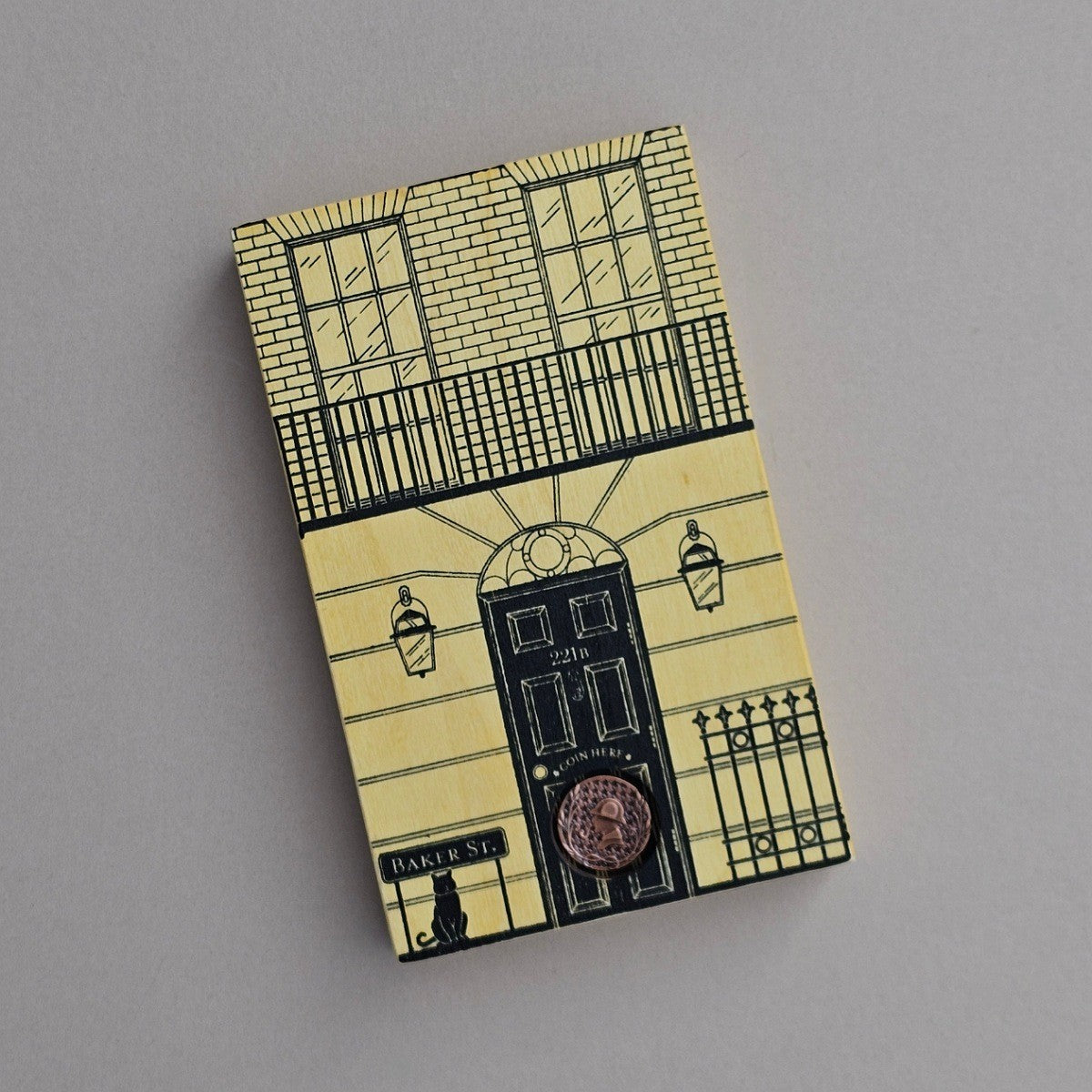 Box with a decorative house design with wording 'Baker Street' on a grey background