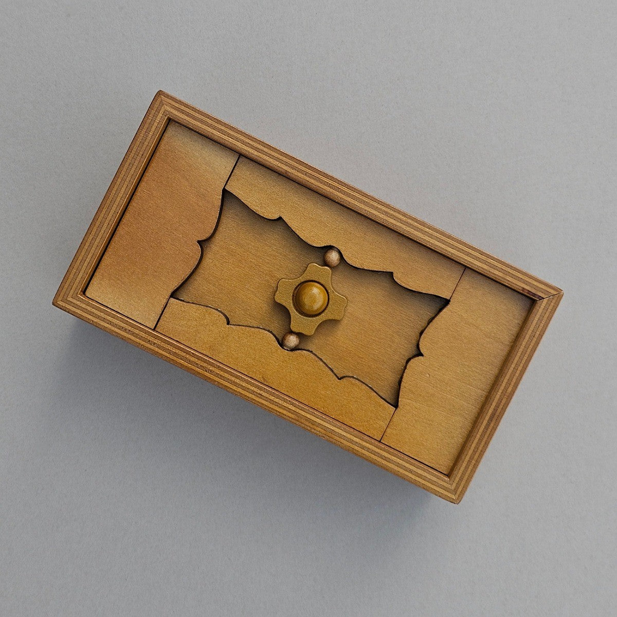 Wooden puzzle box with a decorative design on a grey background