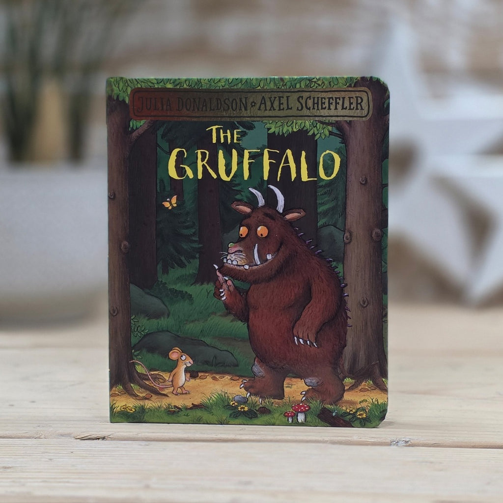 Children's book 'The Gruffalo' by Julia Donaldson and Axel Scheffler on a wooden surface. The Gruffalo and the Mouse are looking at each other.