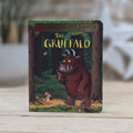 Children's book 'The Gruffalo' by Julia Donaldson and Axel Scheffler on a wooden surface. The Gruffalo and the Mouse are looking at each other.