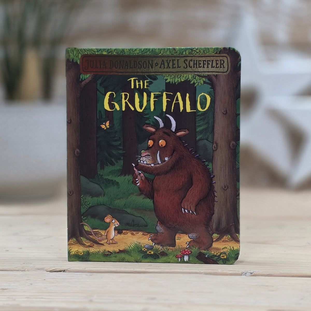 Children's book 'The Gruffalo' by Julia Donaldson and Axel Scheffler on a wooden surface. The Gruffalo and the Mouse are looking at each other.