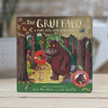 The Gruffalo children's book standing upright on a light wooden surface. The cover shows the brown Gruffalo in a forest with a red push-hole ring, and the title 'The Gruffalo' is printed at the top.