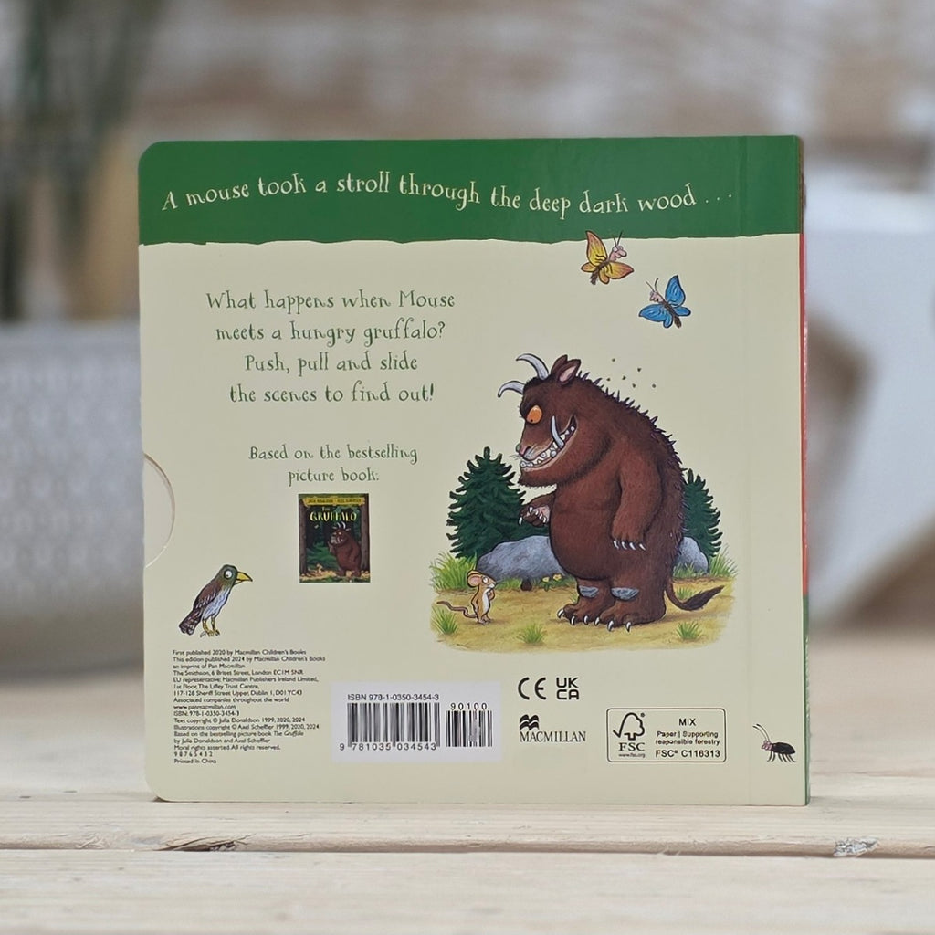 The back cover of the children's book 'The Gruffalo' by Julia Donaldson and Axel Scheffler, resting on a light wooden surface. The cover features a cream-colored background with a green banner at the top, black text, and an illustration of the brown Gruffalo character.