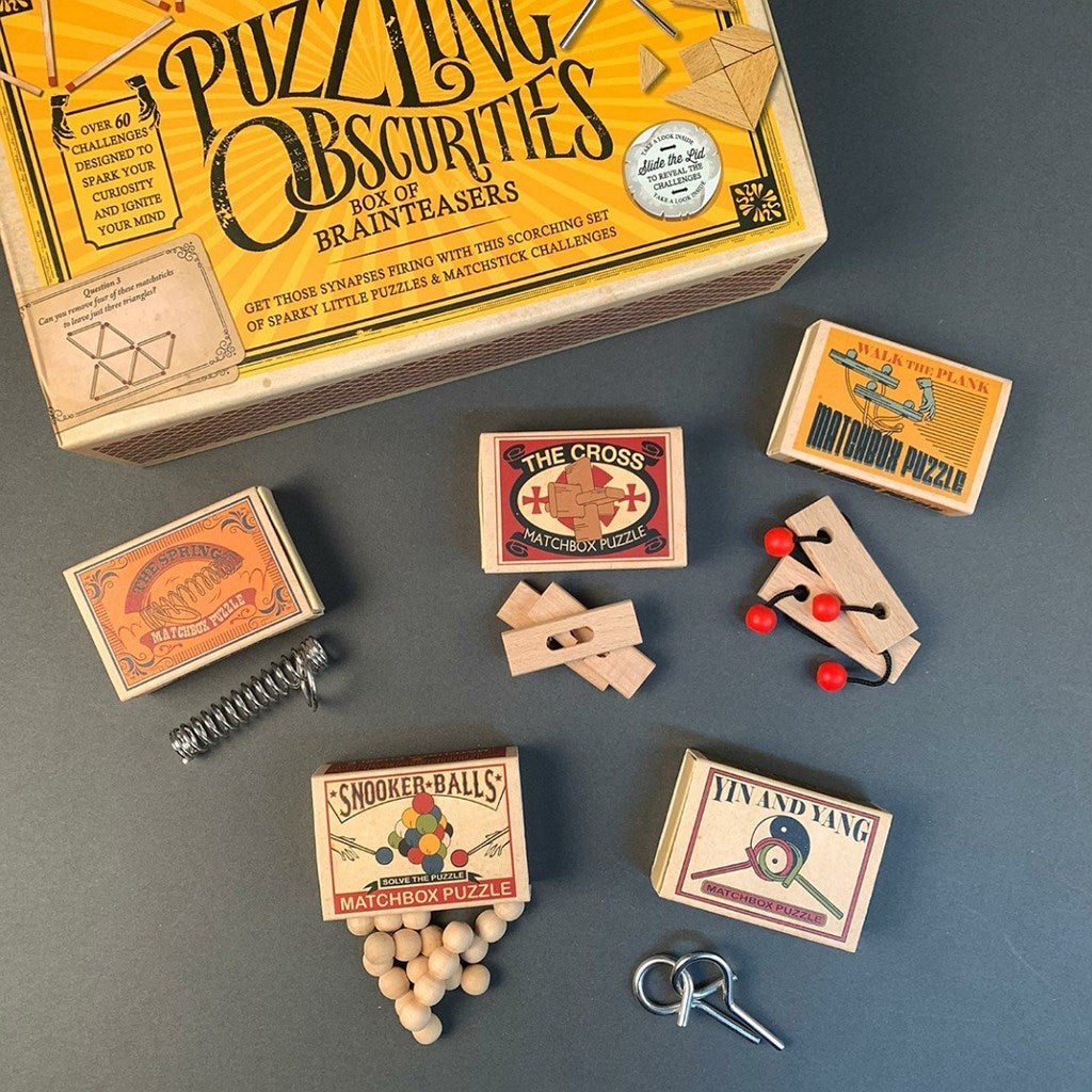 Collection of matchbox puzzles and a box labeled 'Puzzling Obscurities' on a grey background