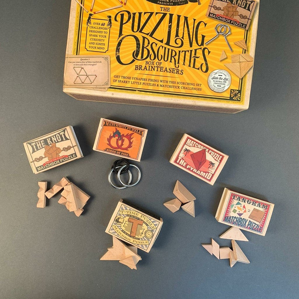 Box of 'The Puzzling Obscurities' matchbox puzzles on a grey background