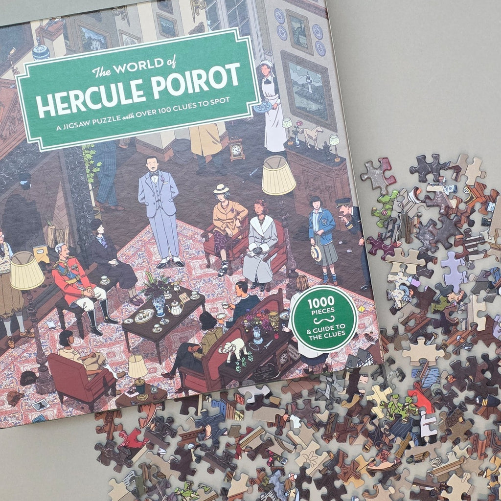 Boxed jigsaw puzzle titled "The World of Hercule Poirot" shown open with many puzzle pieces scattered around it on a light grey surface. The box features a vintage illustrated scene with people in a living room, and a green badge says "1000 pieces to solve the clues.