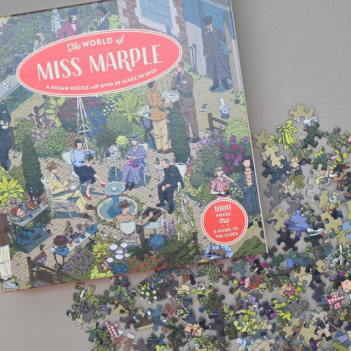 Jigsaw puzzle box titled 'The World of Miss Marple' with scattered puzzle pieces on a flat beige surface
