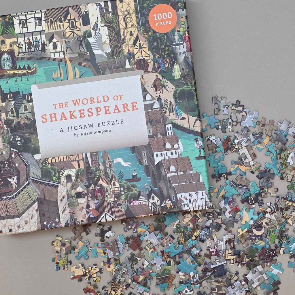The World of Shakespeare A Jigsaw Puzzle by Adam Simpson, showing the illustrated puzzle box with many loose puzzle pieces scattered on a light beige surface.