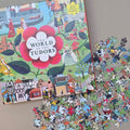 Jigsaw puzzle box titled 'The World of the Tudors' with scattered puzzle pieces on a flat beige surface